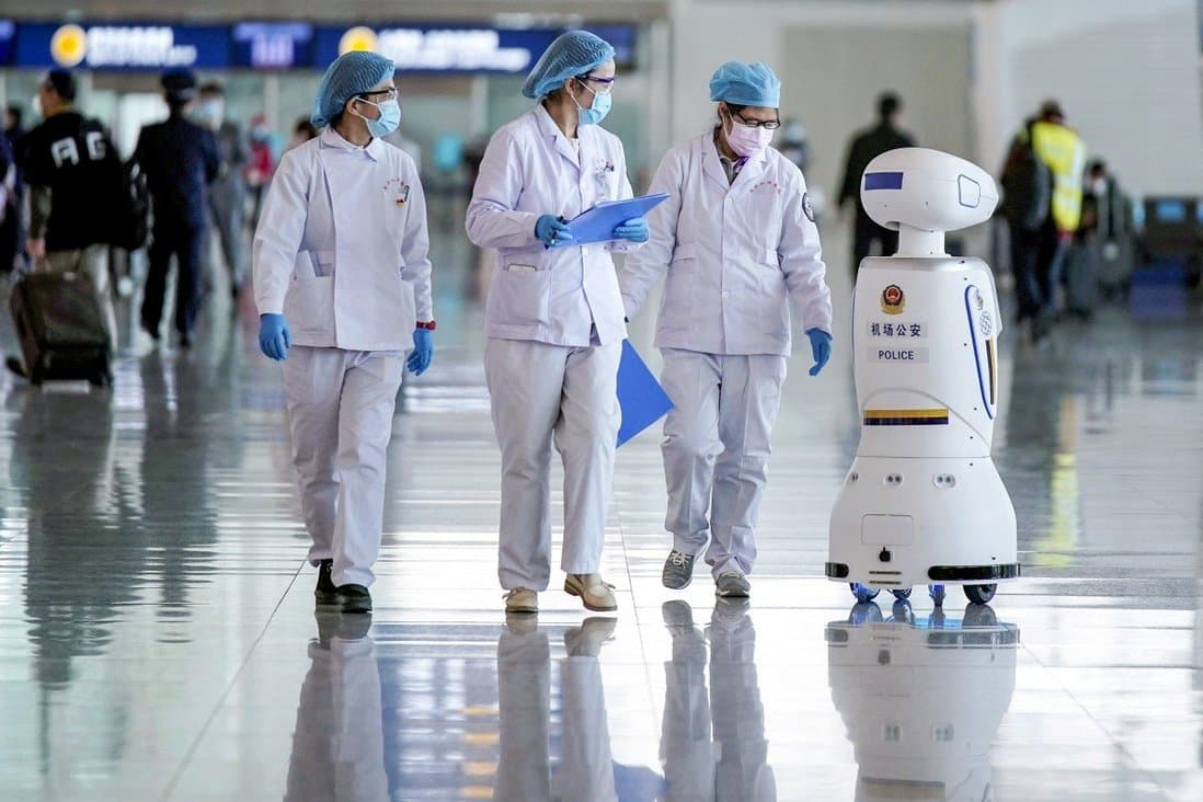 Medical workers walk by a police robot at the Wuhan Tianhe International Airport after travel restrictions to leave Wuhan. April 8, 2020. (Credit: Reuters)